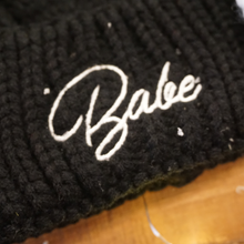 Load image into Gallery viewer, Soft black beanie with &#39;Babe&#39; in white embroidery and faux fur pom-pom. Perfect for bachelorette parties or winter wear.
