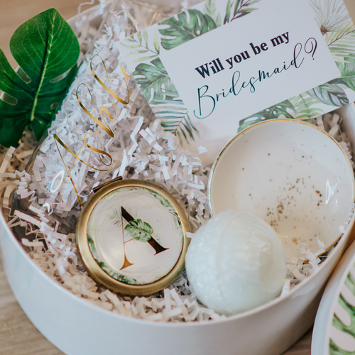 A compact mirror with a tropical design, featuring palm leaves in shades of green and accents of gold on the top. The top can be monogrammed with your initials, and its small size makes it easy to fit in a purse or makeup bag. Perfect for on-the-go touch-ups and checking your appearance.