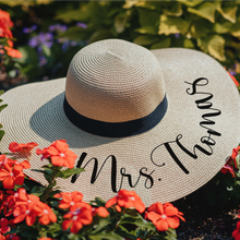 Load image into Gallery viewer, Stylish wide brim floppy hat, made with high-quality straw for maximum sun protection and personalized with a Mrs. [Last Name]&quot; in black script text and finished with a black ribbon band. Perfect for brides, bachelorette parties, or any outdoor adventure.

